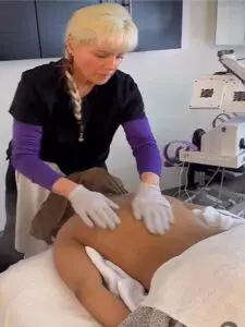 A woman in purple gloves is waxing her legs.