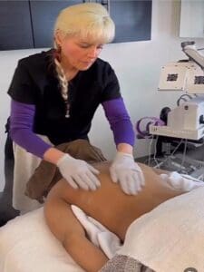 A woman in purple gloves is waxing her legs.