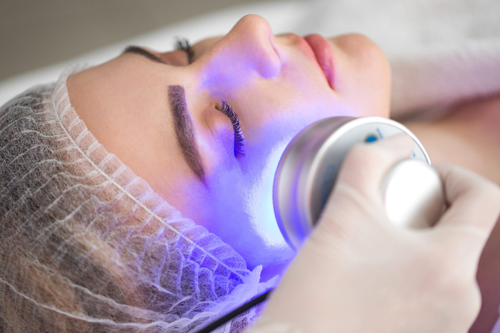 Ultrasonic massager. Light skin treatment, the woman in the beauty salon. LED Skin Care Spa