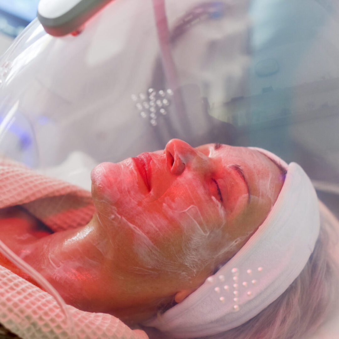 Woman receiving LED facial therapy for face. LED Skin Care Spa